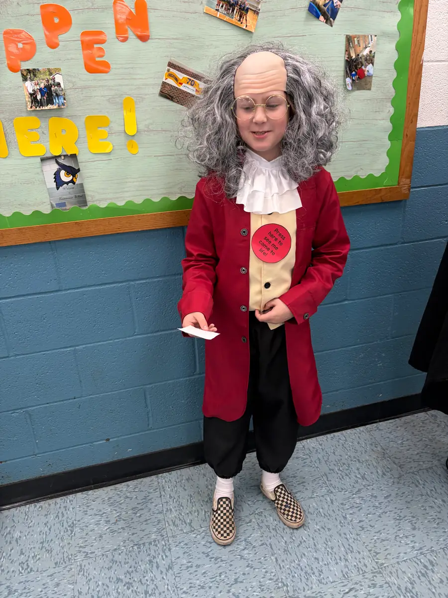 Student dressed as Benjamin Franklin in a red coat and white wig