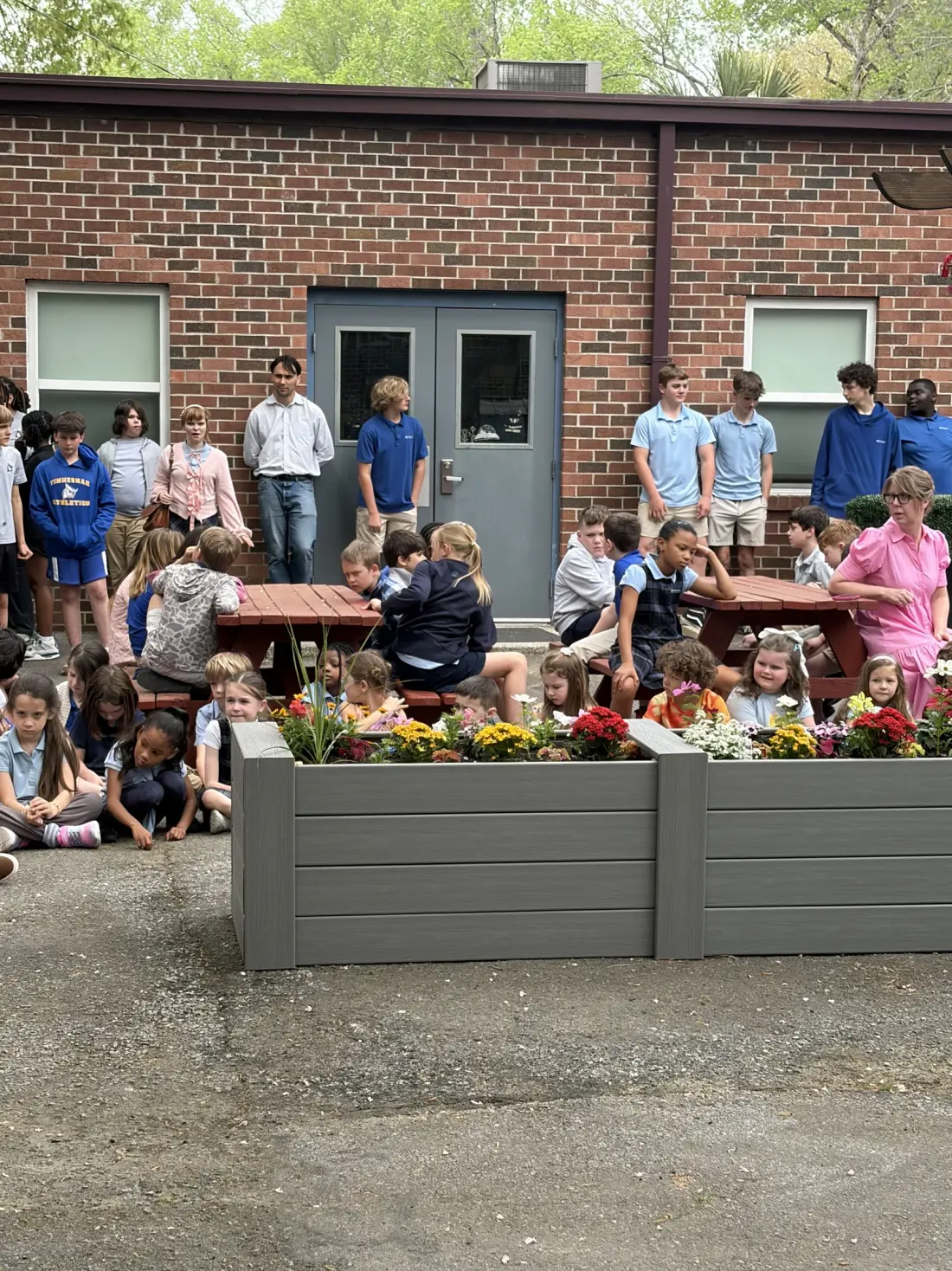 Students and adults beside new flower beds and refinished picnic tables in the Moody Memorial Garden