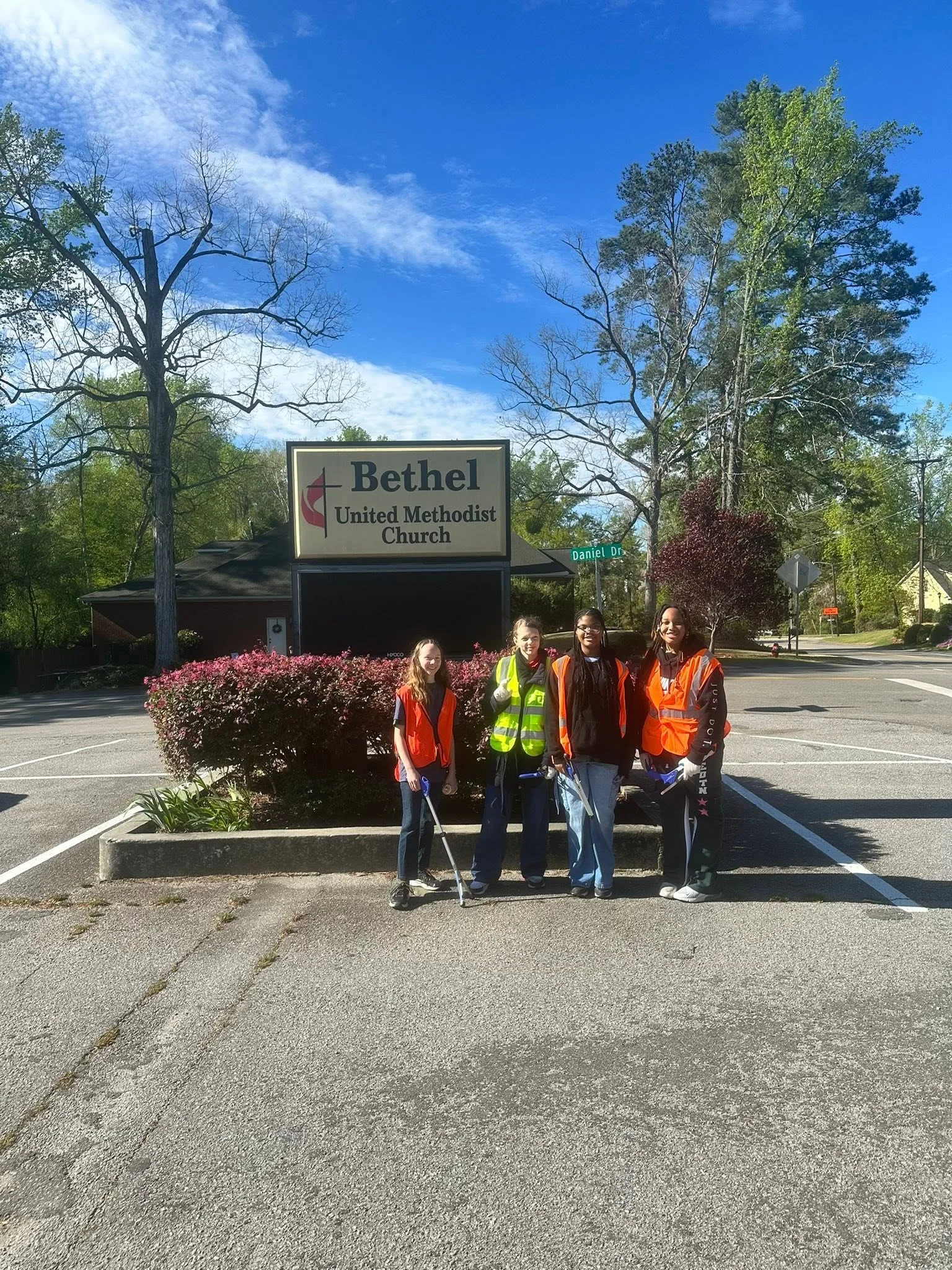 Students in safety vests cleaning Bethel Church grounds
